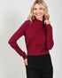 Woman wearing a maroon long-sleeve top against a white background