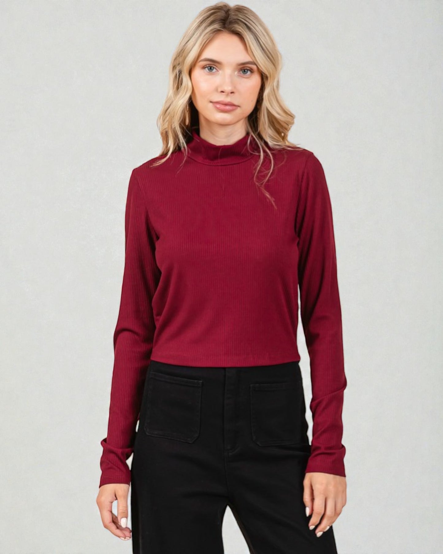 Woman wearing a burgundy long-sleeve top against a plain background