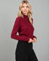 Woman wearing a burgundy turtleneck sweater against a gray background