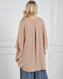 Person wearing a beige oversized sweater against a white wall