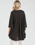 Person wearing a dark gray poncho over a white outfit on a light gray background