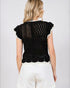 Woman wearing a black knitted top with white trim on a plain background