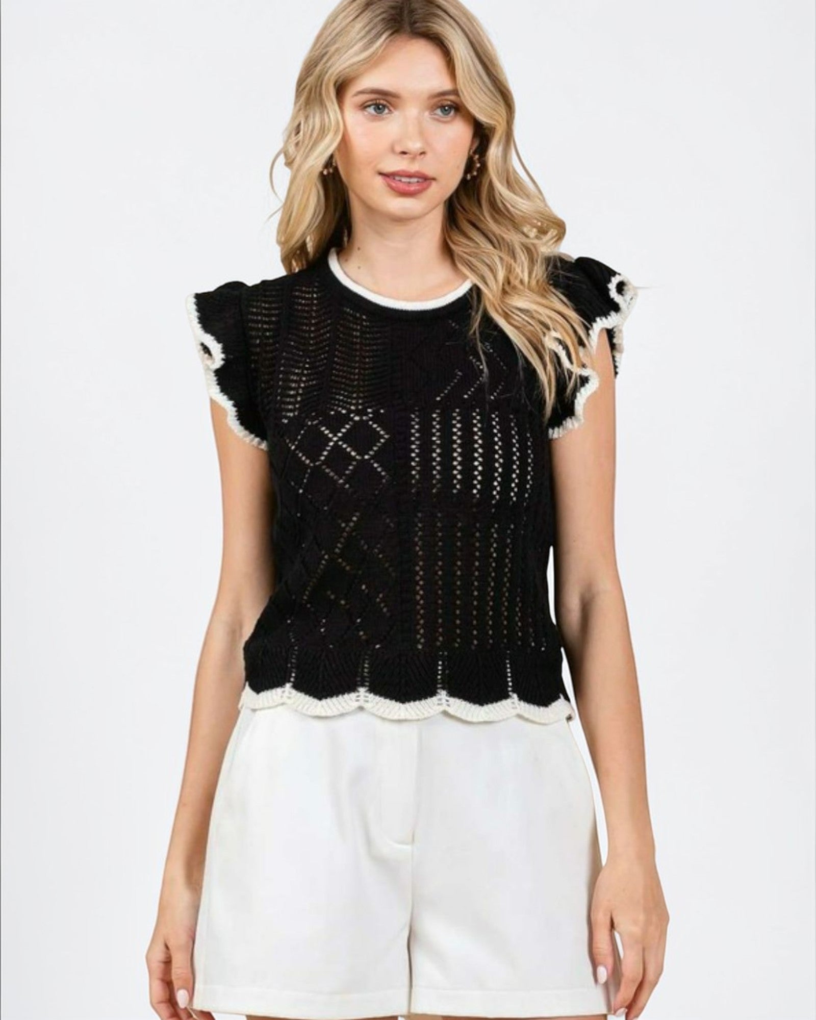 Woman wearing a black and white patterned top with a plain background