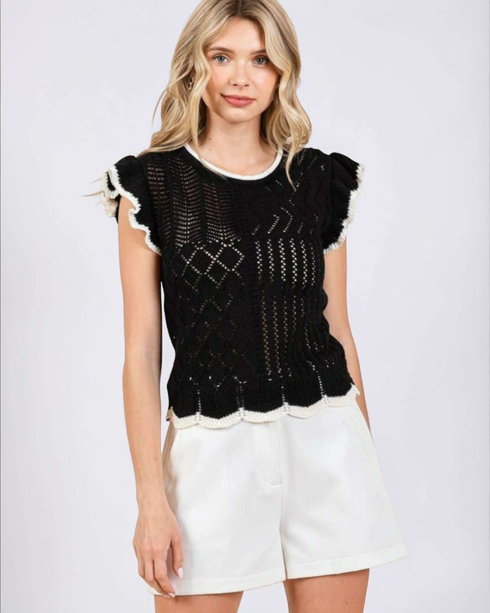 Woman wearing a black and white patterned top with a plain background