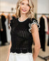 Woman wearing a black sleeveless top with white details in a clothing store.