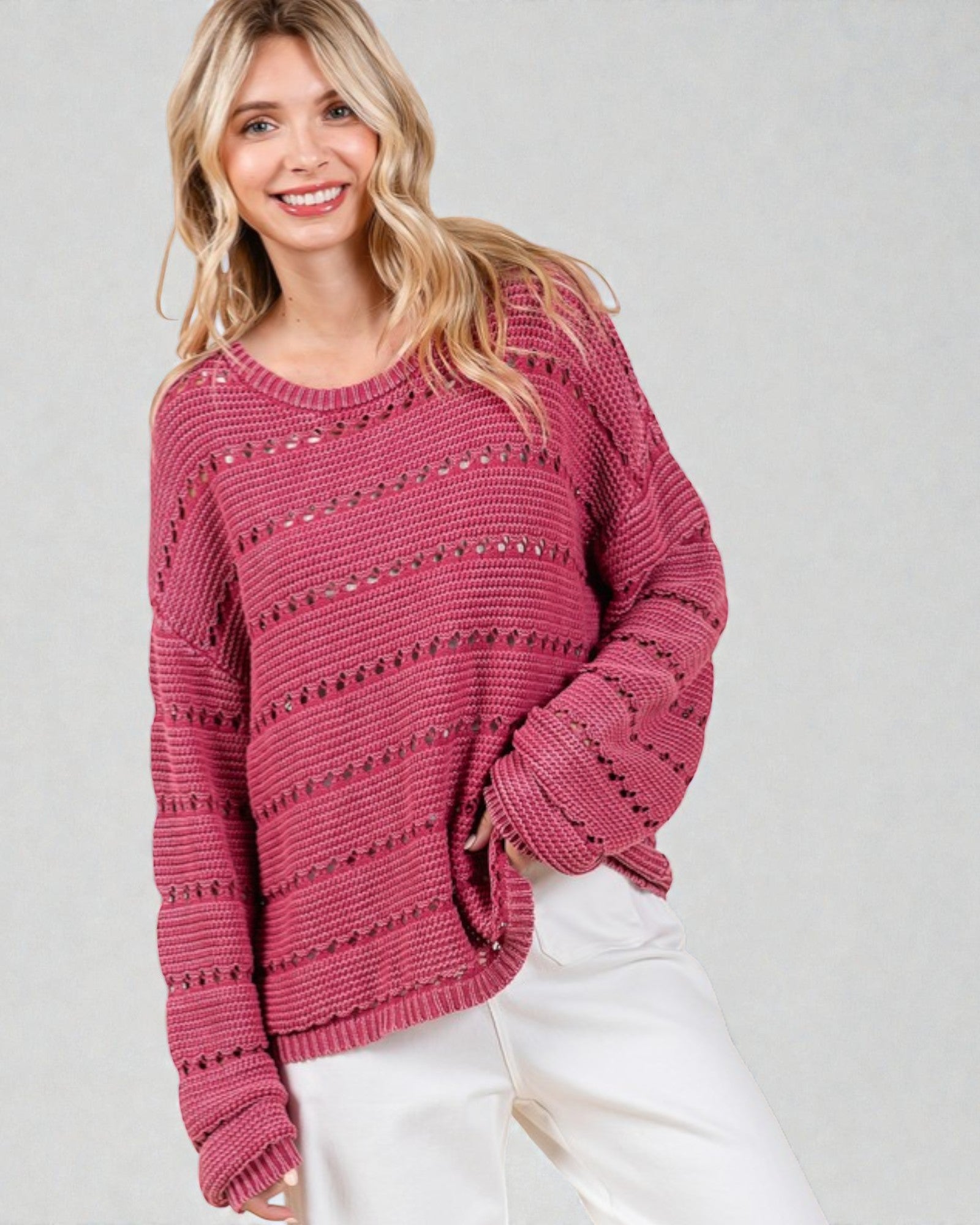 Woman wearing a pink knitted sweater on a plain background