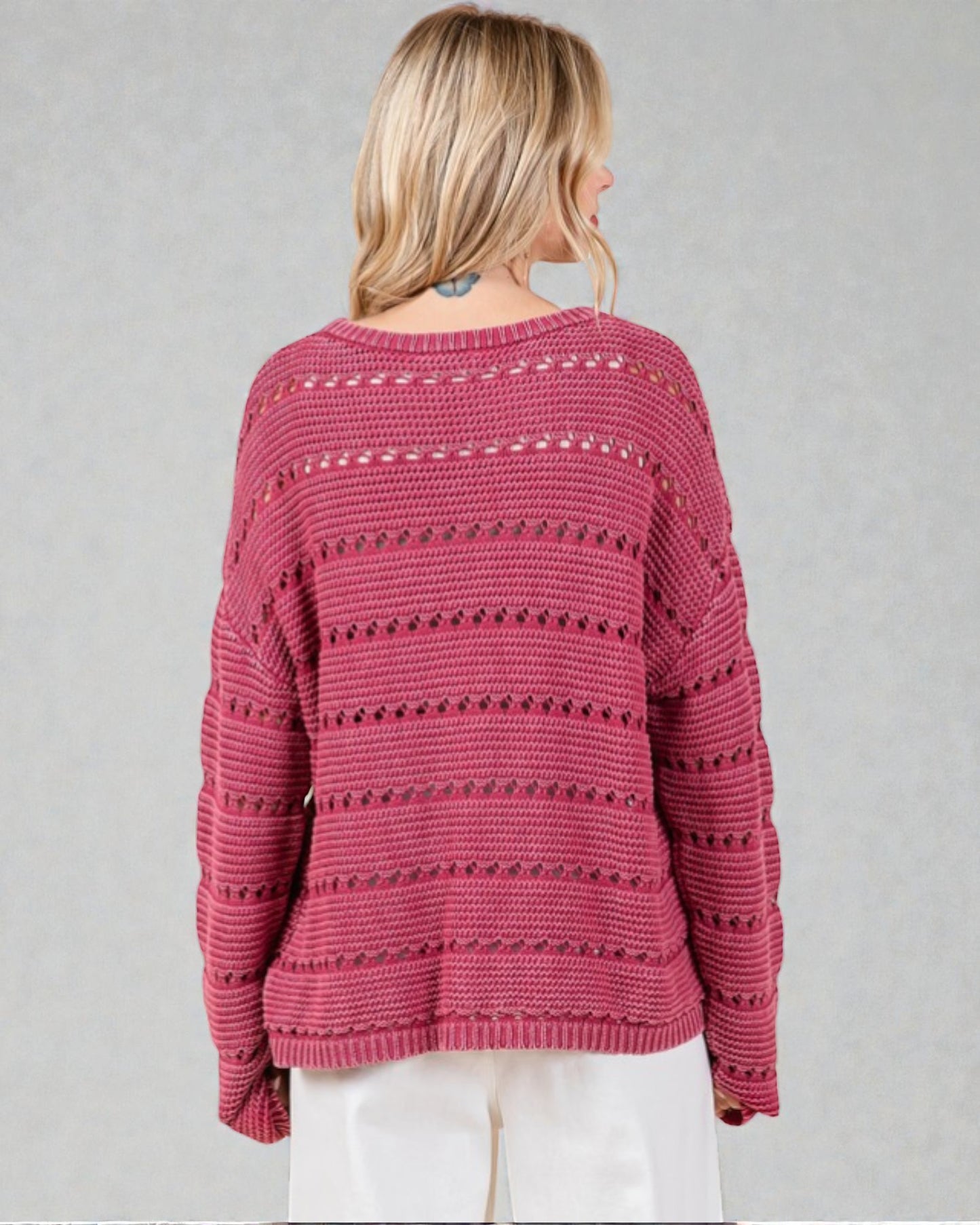 Person wearing a patterned pink sweater on a plain background