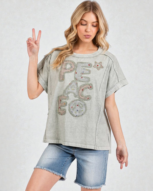 Woman wearing a gray t-shirt with 'PEACE' text and denim shorts on a white background