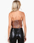 A woman shown from the back wearing a textured, snakeskin-patterned spaghetti-strap top and black faux-leather pants, against a plain white studio background.