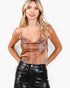 A woman modeling a patterned camisole top with thin straps and a gathered bust, paired with black faux-leather pants, against a plain light background.