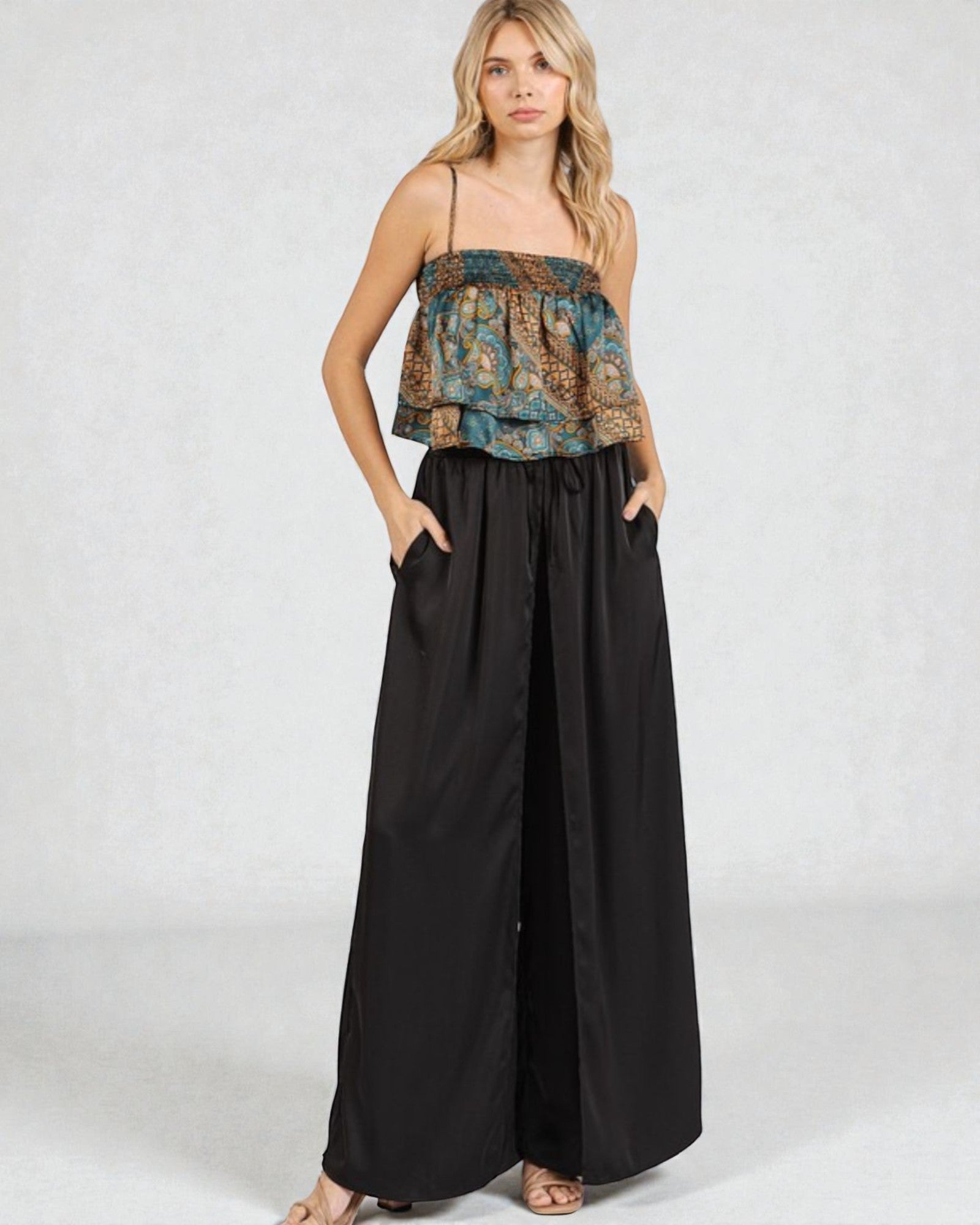 Woman wearing a floral top and black wide-leg pants on a white background