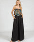 Woman wearing a floral top and black wide-leg pants on a white background