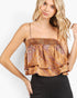 A woman wearing a smocked camisole top with a rust-orange and brown paisley pattern, paired with black pants, against a plain white background.