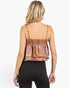 A woman shown from the back wearing a smocked camisole top with a rust-orange and brown paisley pattern, paired with black leggings, against a plain white background.