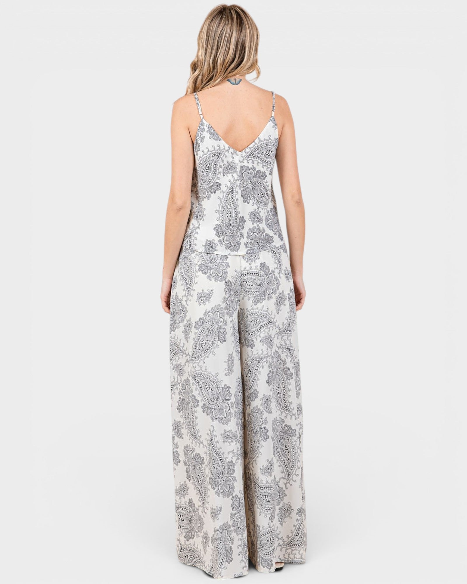 Woman wearing a white floral patterned jumpsuit on a white background