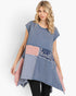 A woman modeling a blue patchwork tunic top with red, white, and blue patterned fabric panels, set against a plain white background.