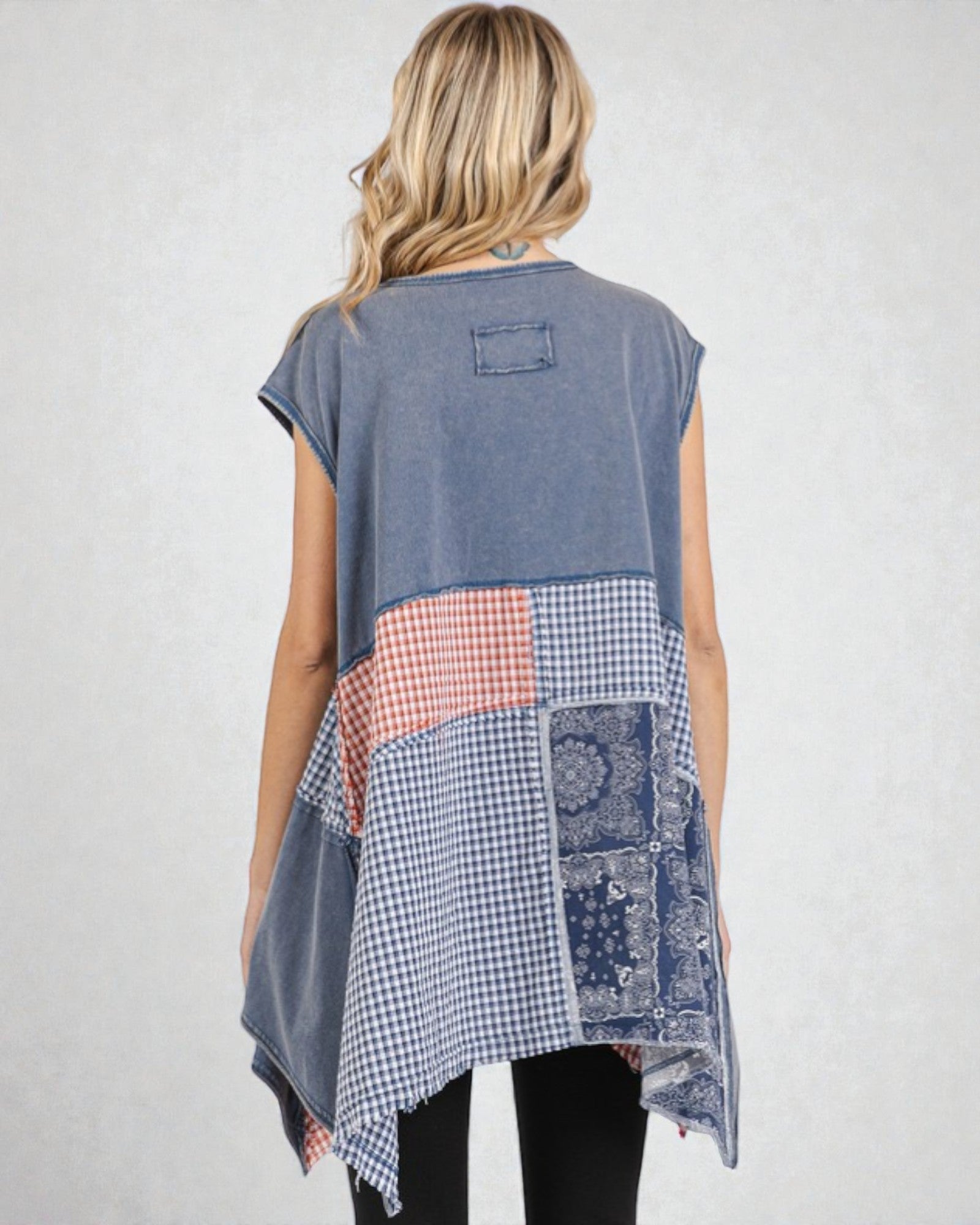 Woman wearing a sleeveless, patchwork-style top with a white background