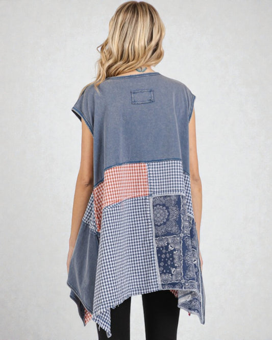 Woman wearing a sleeveless, patchwork-style top with a white background