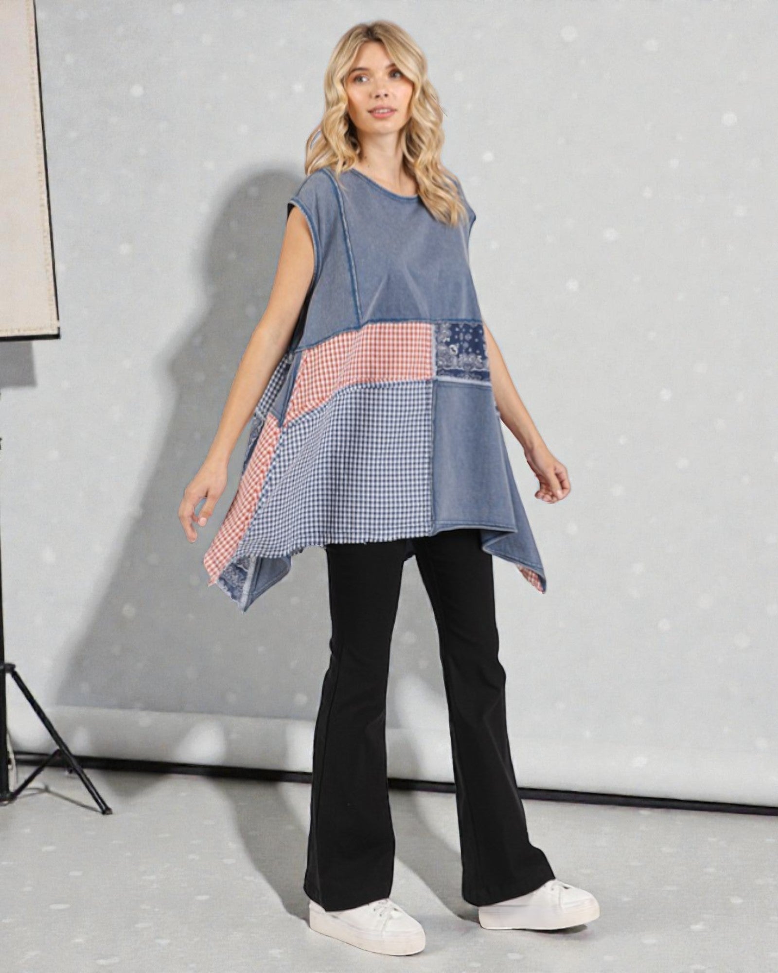 Woman wearing a blue patchwork dress with a plain background