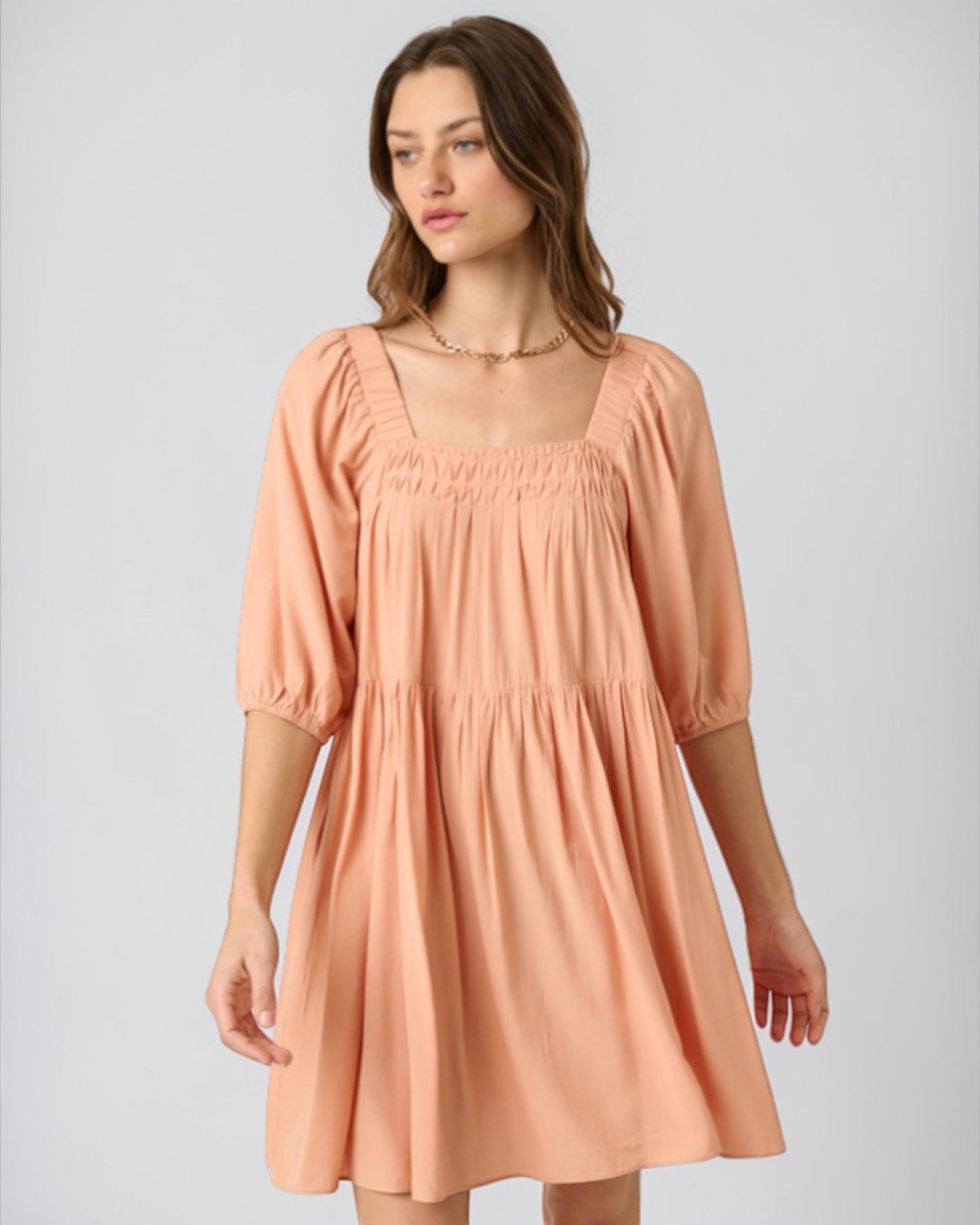 Woman wearing a peach-colored dress on a plain background