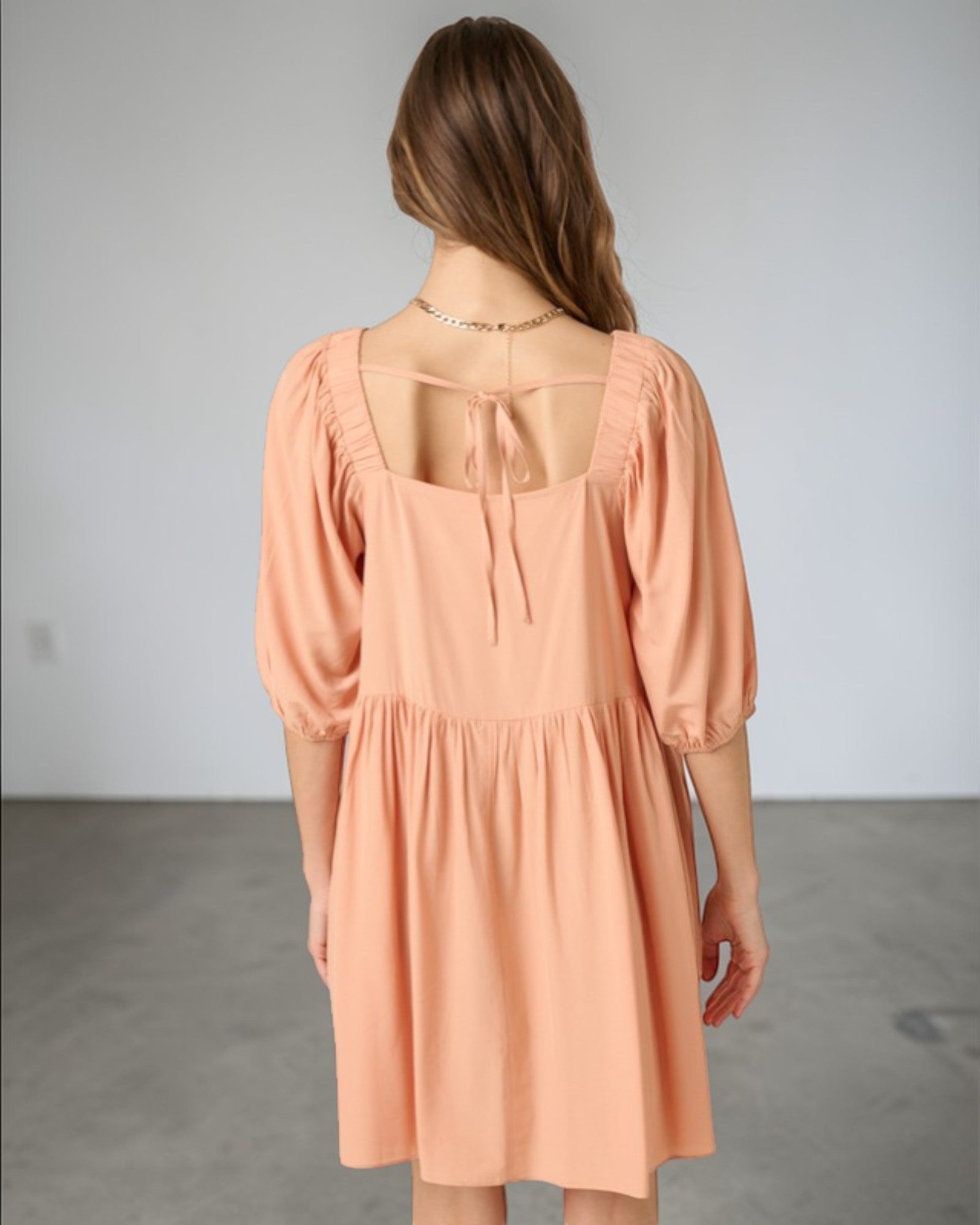 Woman wearing a peach dress with a plain background