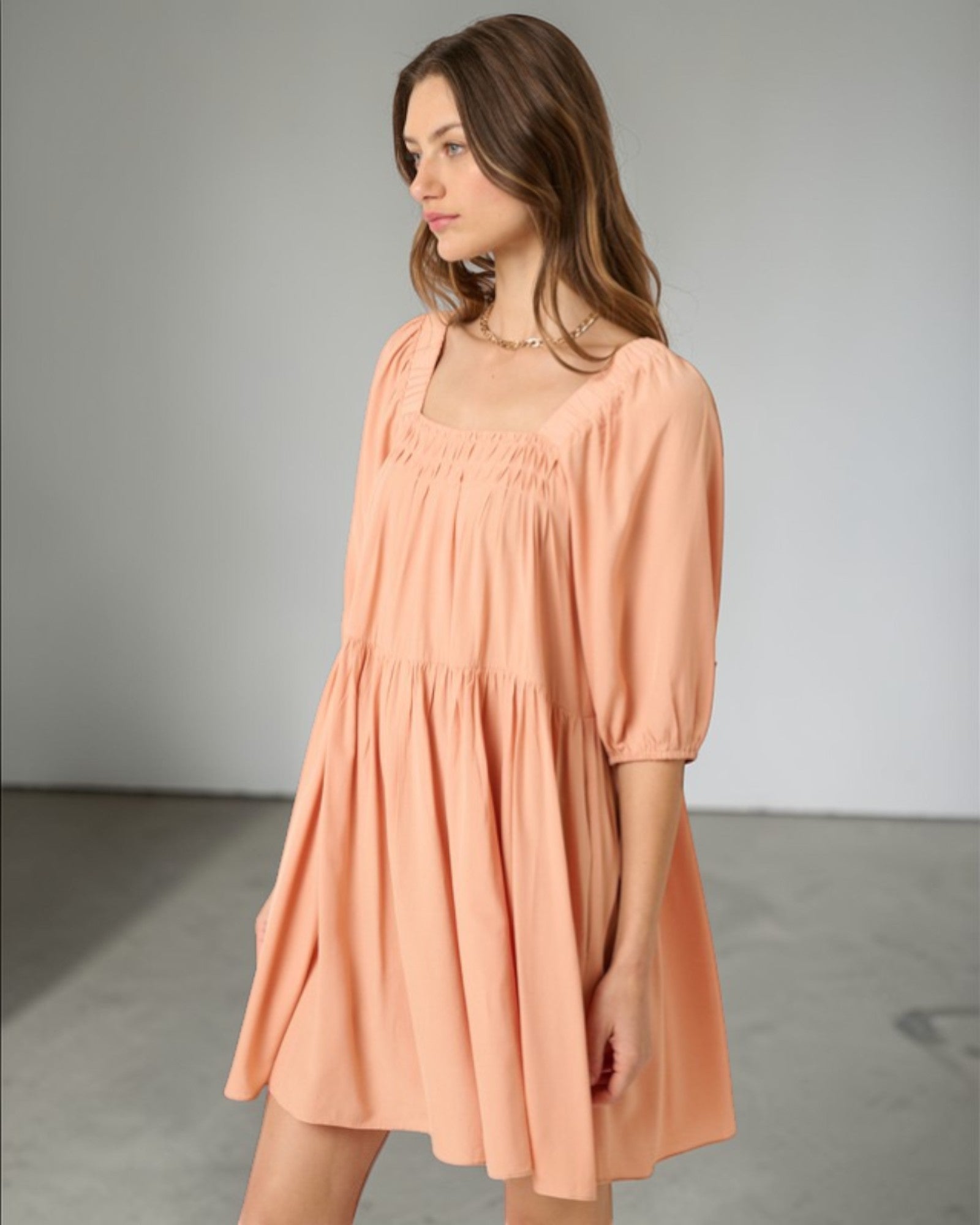 Woman wearing a peach-colored dress against a plain background