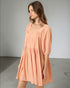 Woman wearing a peach-colored dress against a plain background
