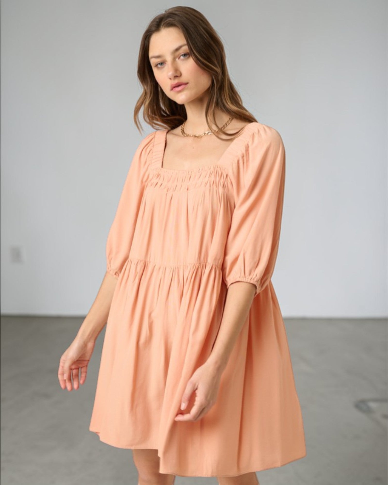 Woman wearing a peach-colored dress against a plain background