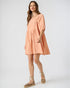 Woman wearing a peach-colored dress on a white background
