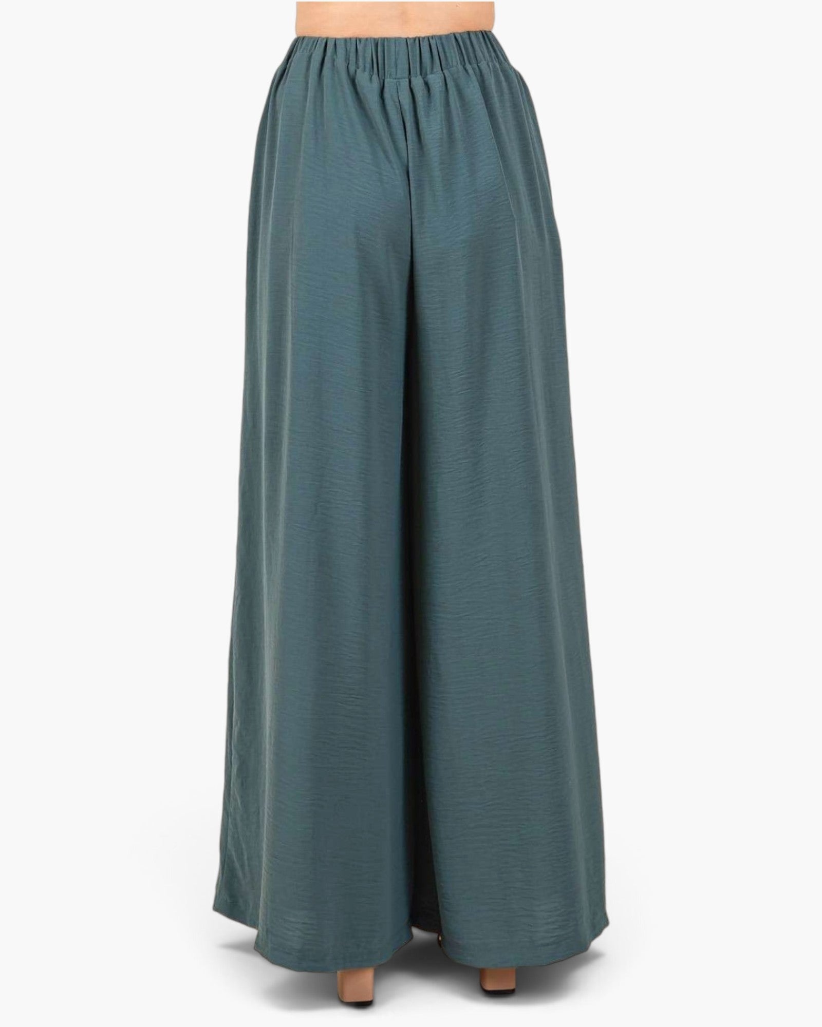 A pair of wide-leg trousers in a muted teal blue-green color, shown on a model from the waist down against a plain white background.