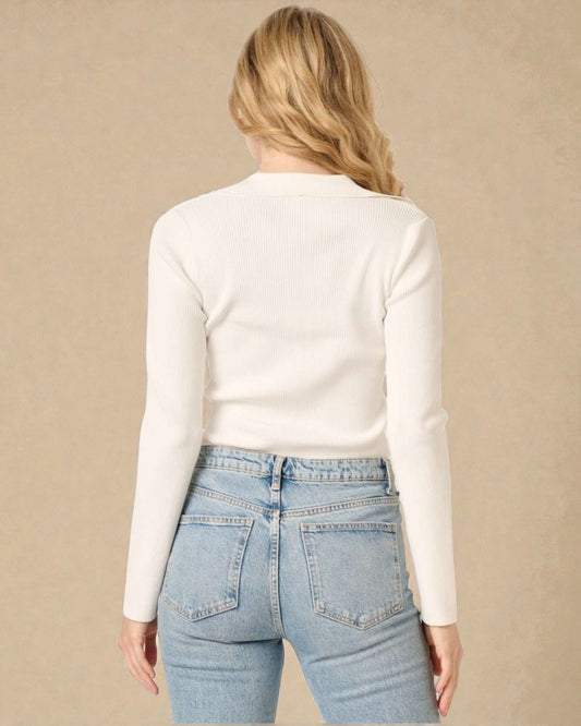 Person wearing a white long-sleeve top and light blue jeans on a beige background