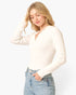 A woman wearing a ribbed long-sleeve polo-style top in off-white, paired with light-wash blue jeans, against a plain white studio background.
