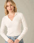 Woman wearing a white long-sleeve top against a plain background