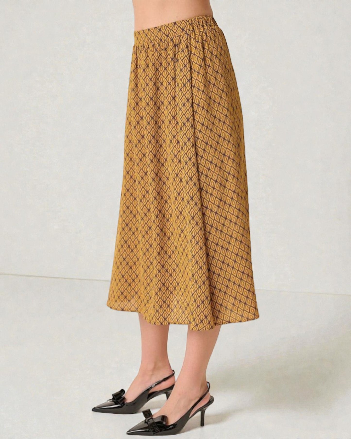 Person wearing a mustard yellow patterned skirt on a white background