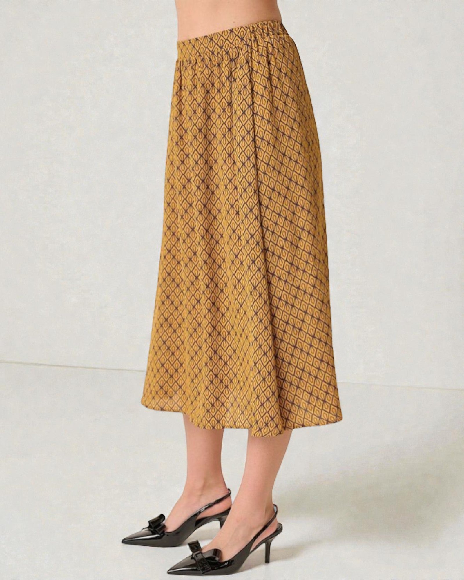 Person wearing a mustard yellow patterned skirt on a white background