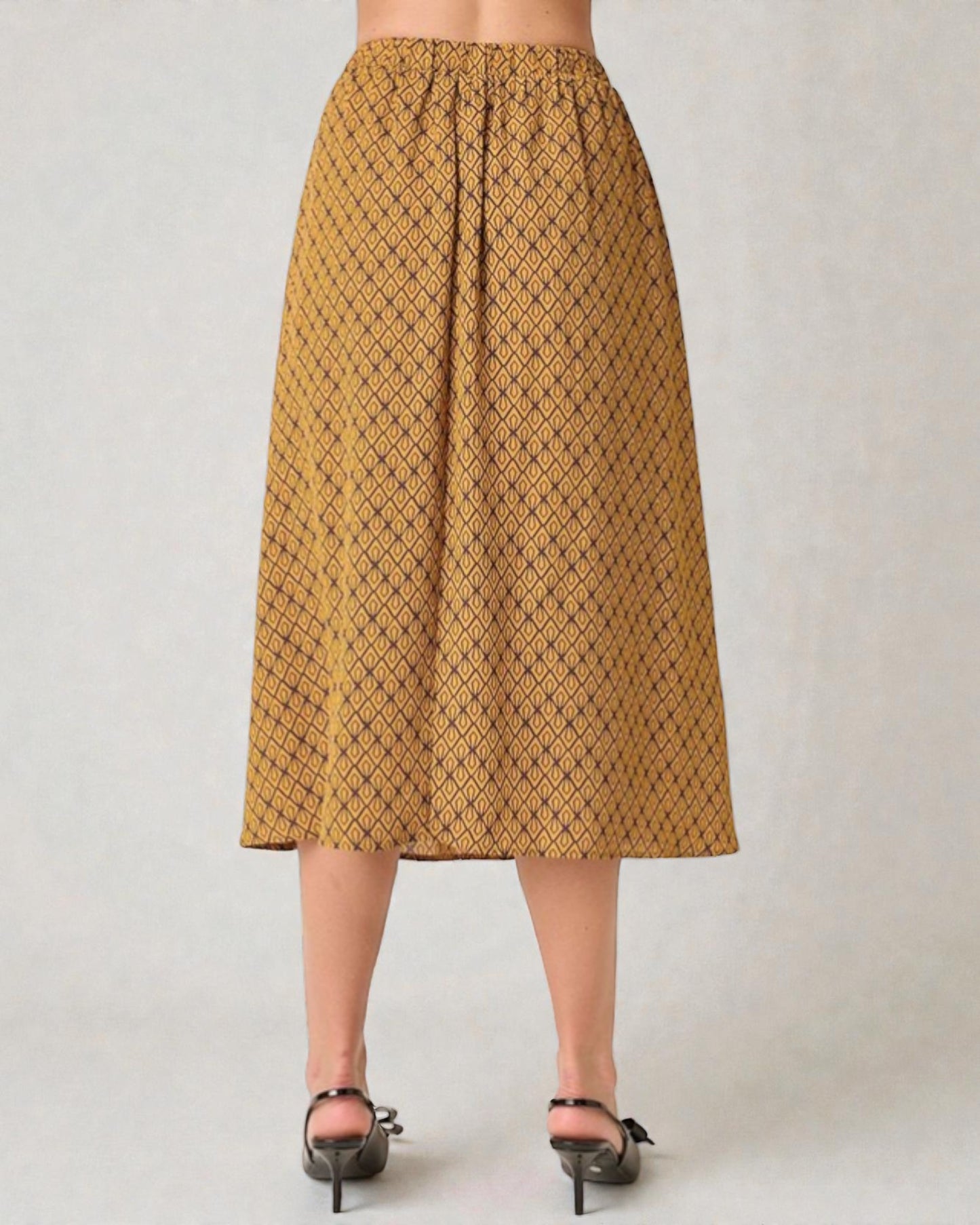 Person wearing a mustard yellow patterned skirt on a plain background