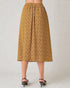 Person wearing a mustard yellow patterned skirt on a plain background
