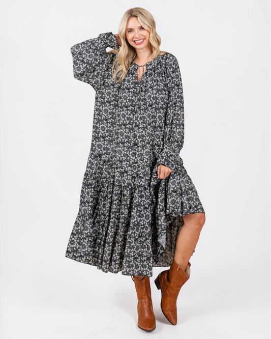 Woman wearing a black floral dress with long sleeves on a white background