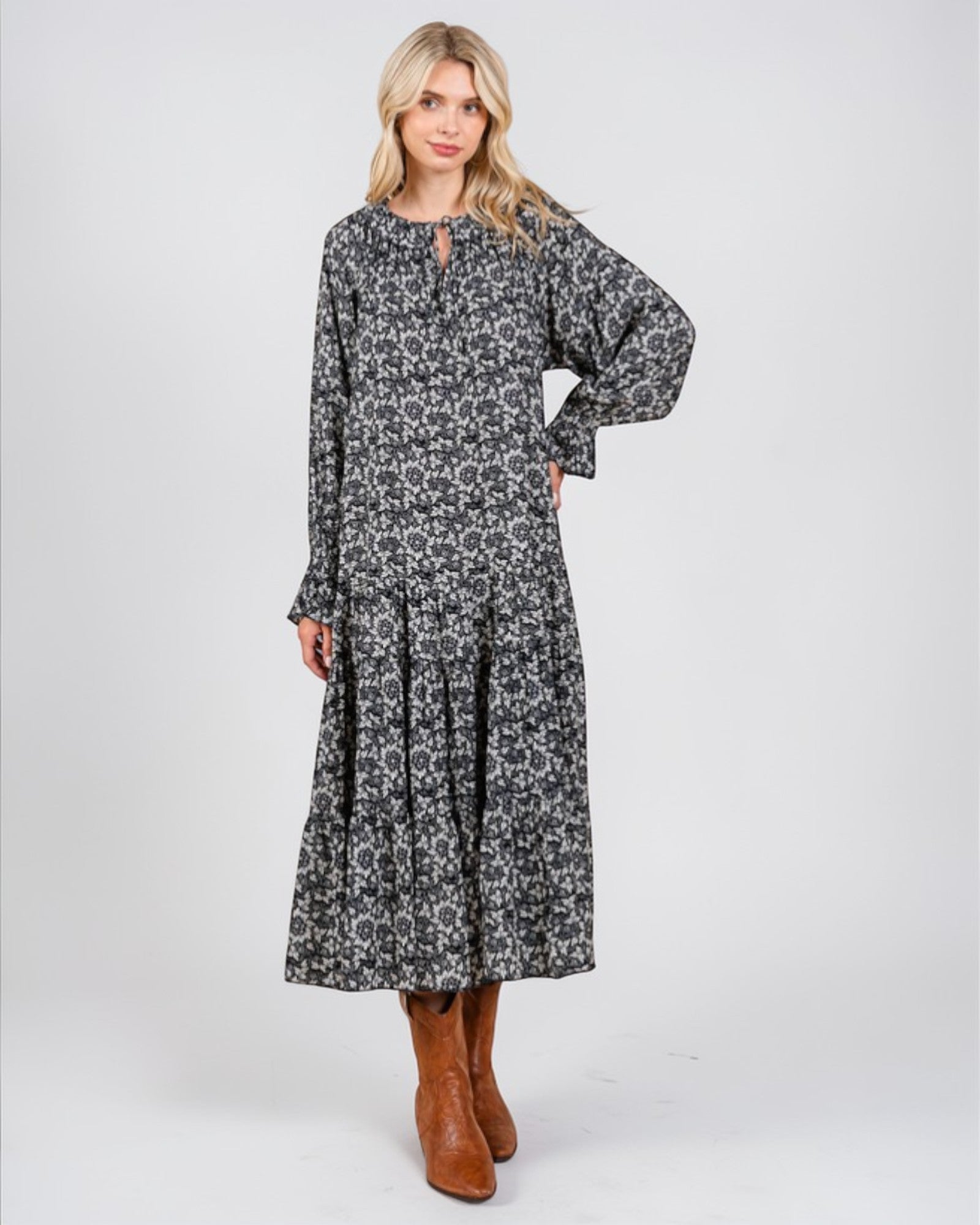 Woman wearing a long floral dress with brown boots on a white background