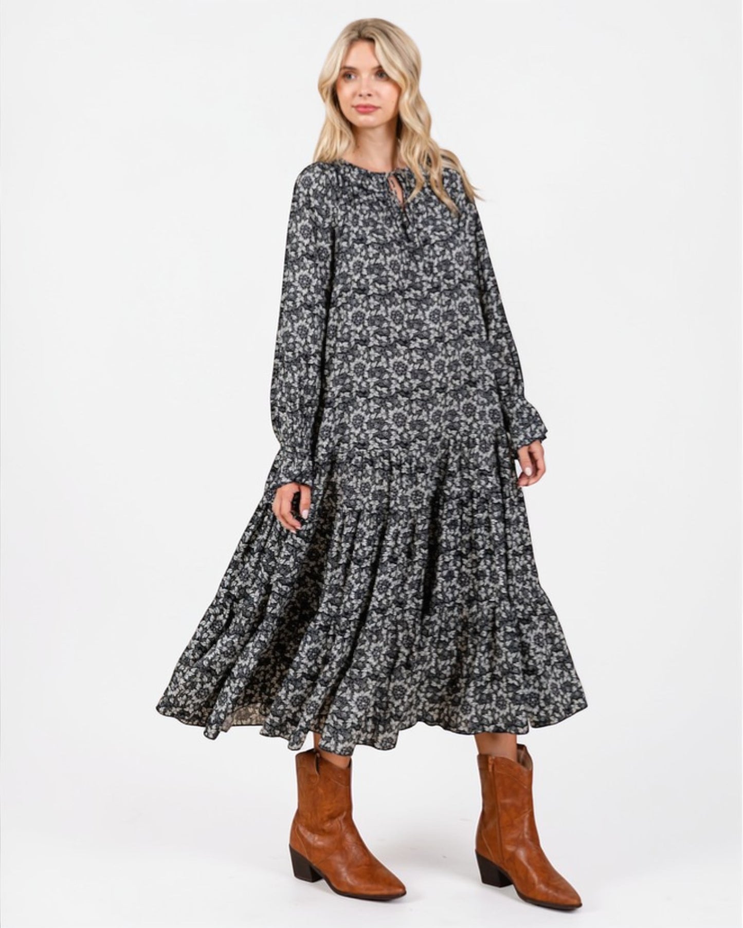 Woman wearing a floral dress with long sleeves and brown boots on a white background
