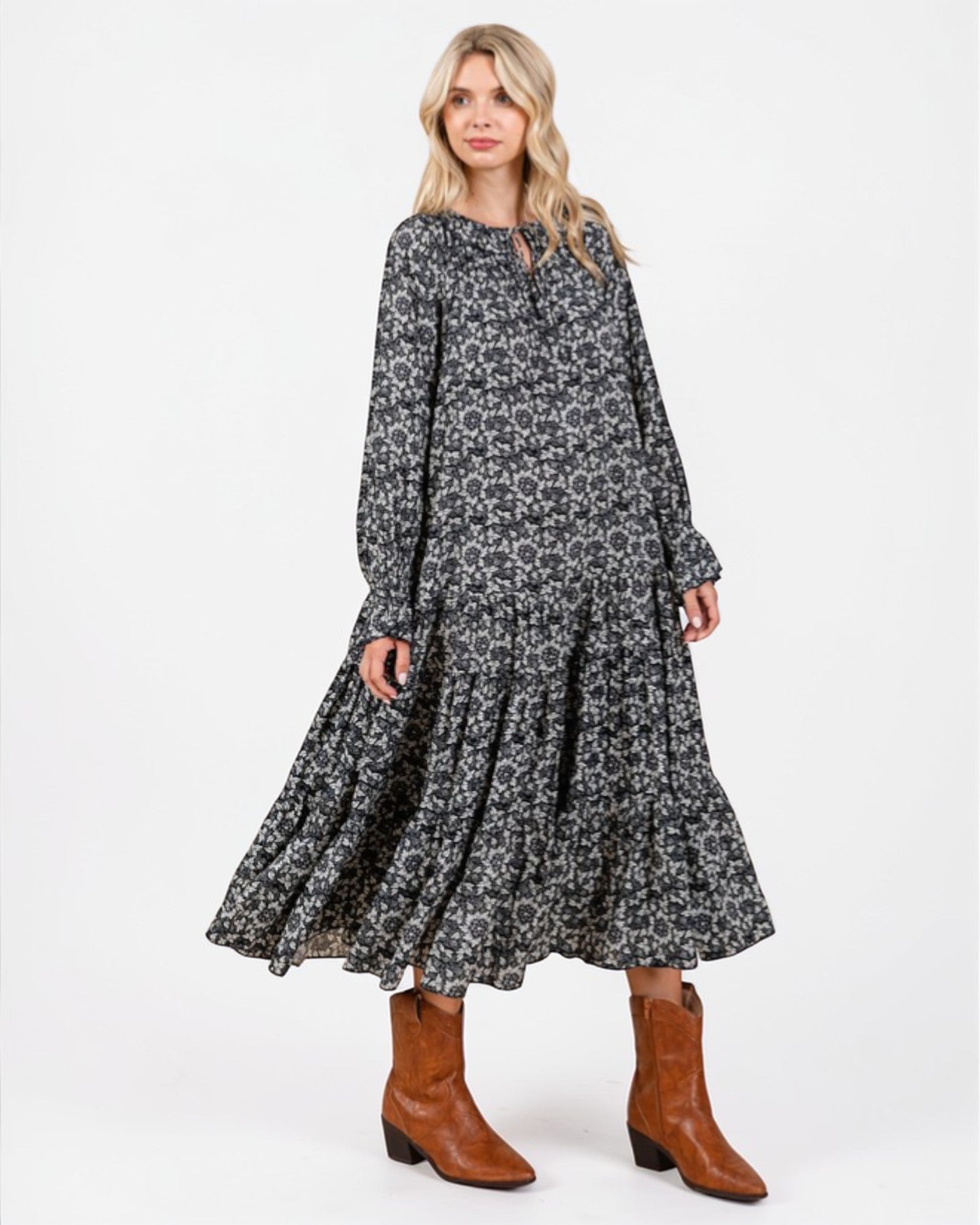 Woman wearing a floral dress with long sleeves and brown boots on a white background