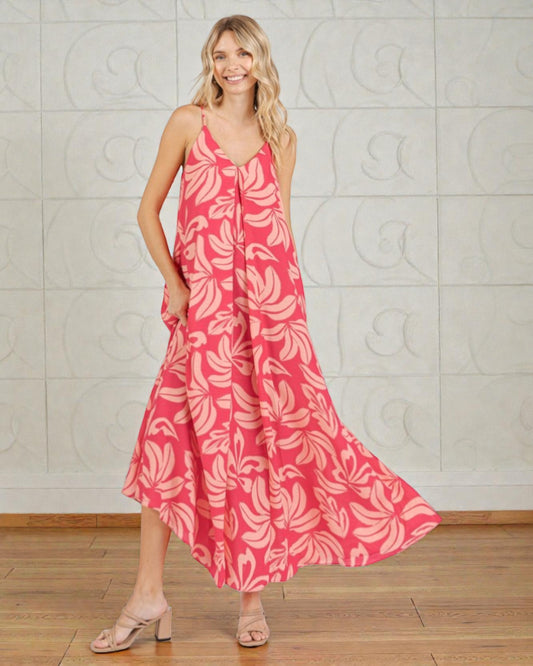 Woman wearing a pink floral dress against a light gray wall.