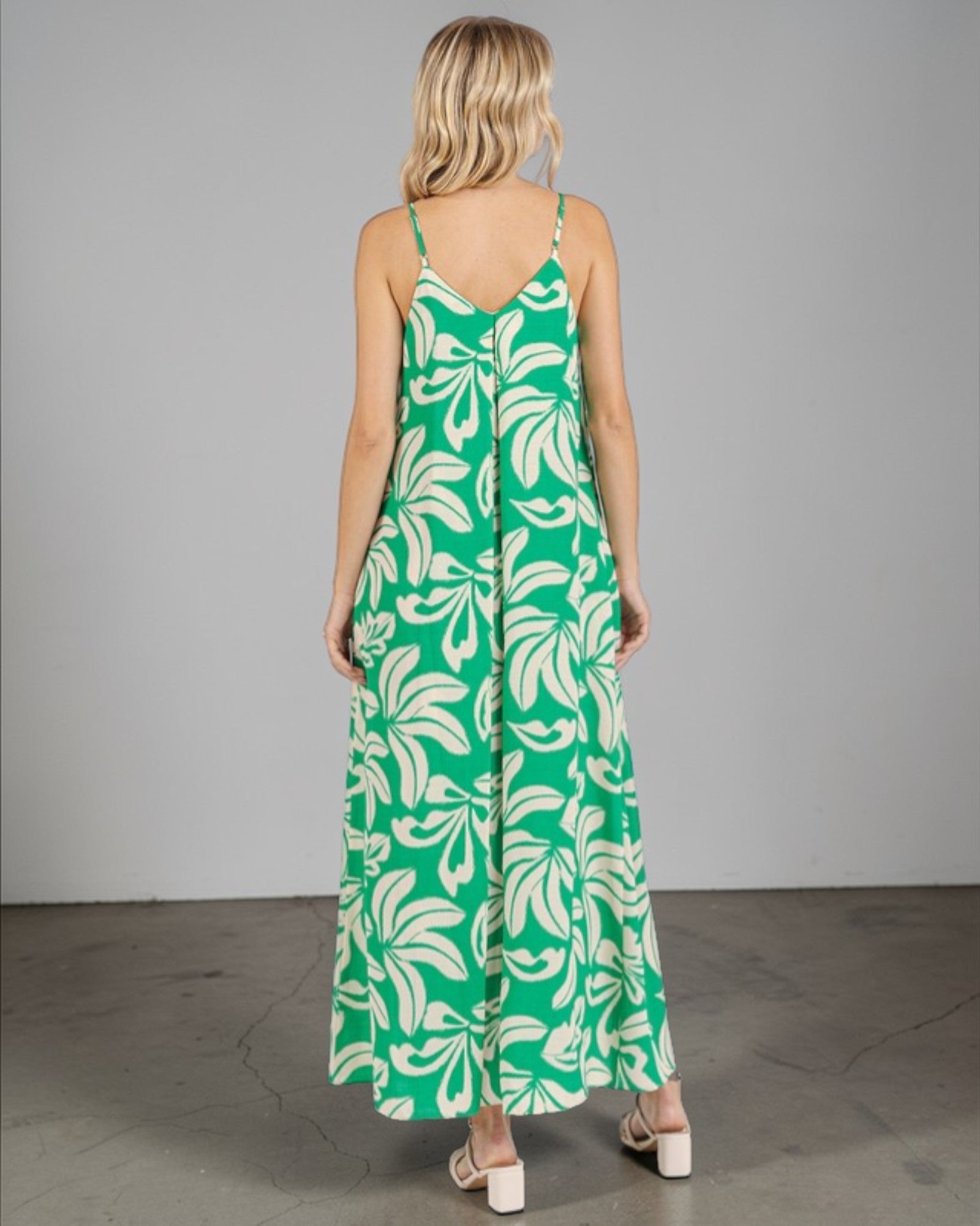 Woman wearing a green and white leaf-patterned dress against a gray background