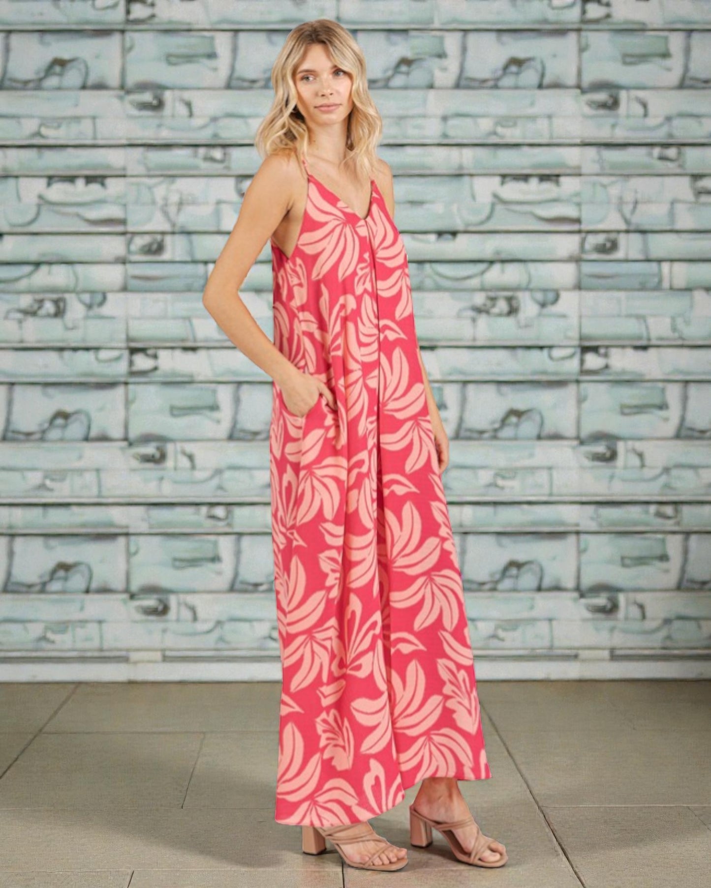 Woman wearing a pink floral dress against a textured wall.