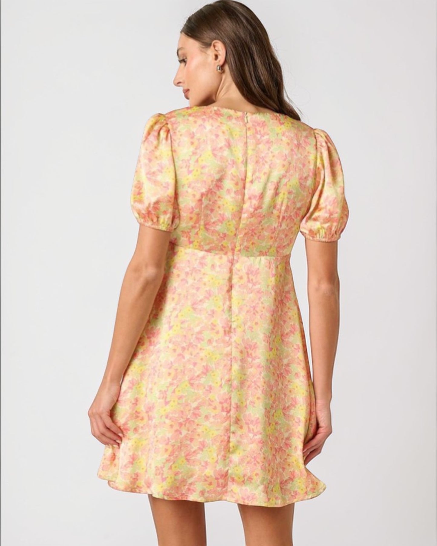 Woman wearing a floral dress with puff sleeves on a plain background