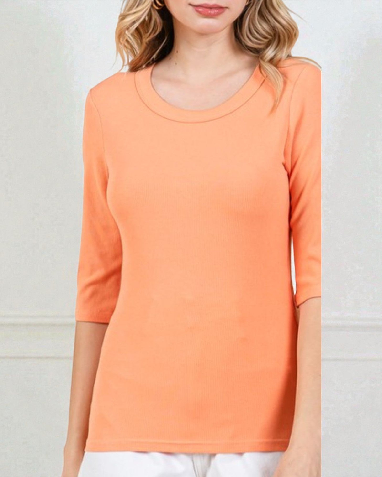 Person wearing an orange long-sleeve top against a plain background