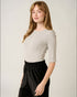 Woman wearing a gray top and black pants on a plain background