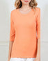 Person wearing an orange long-sleeve top against a plain background