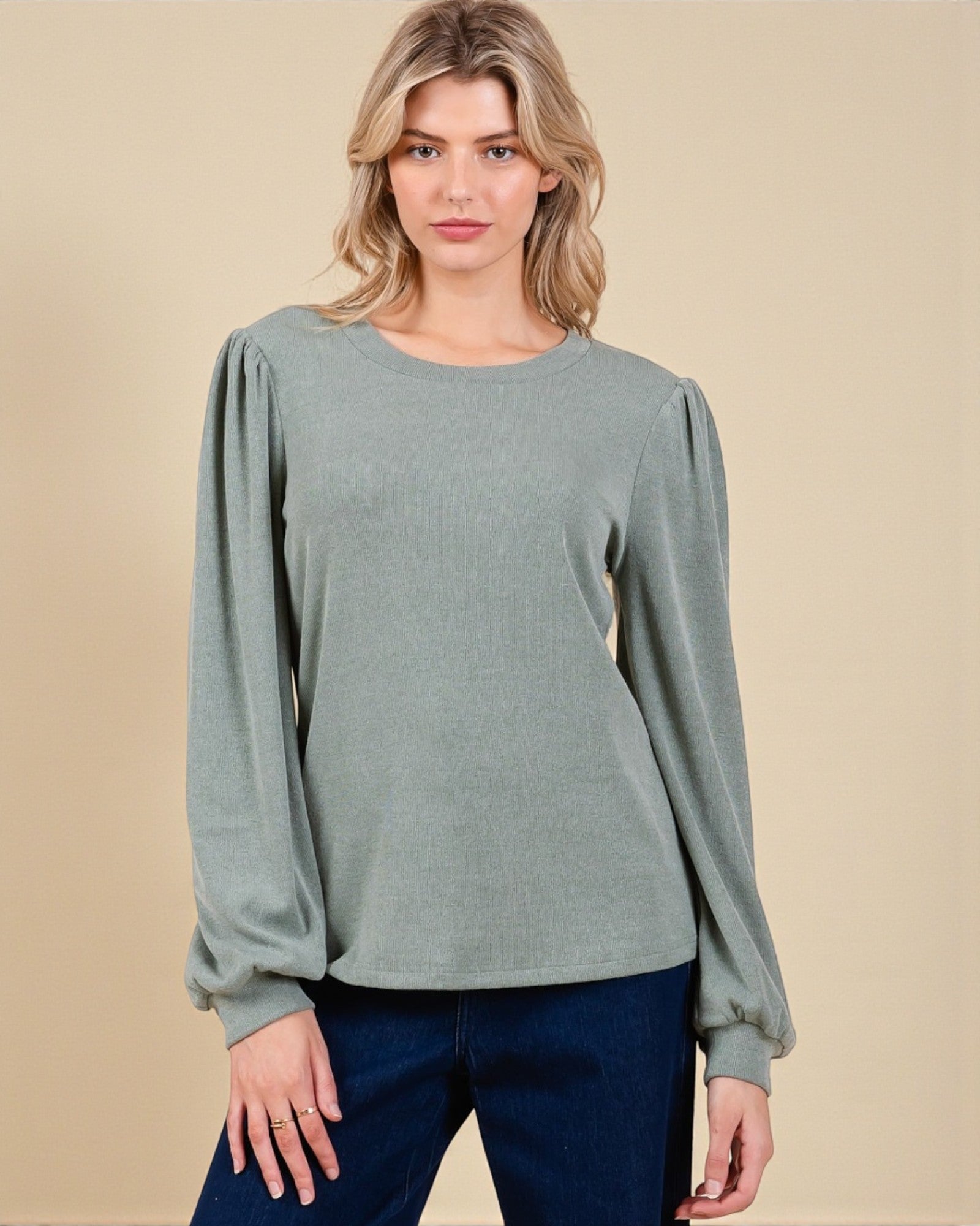 Woman wearing a gray long-sleeve top against a beige background