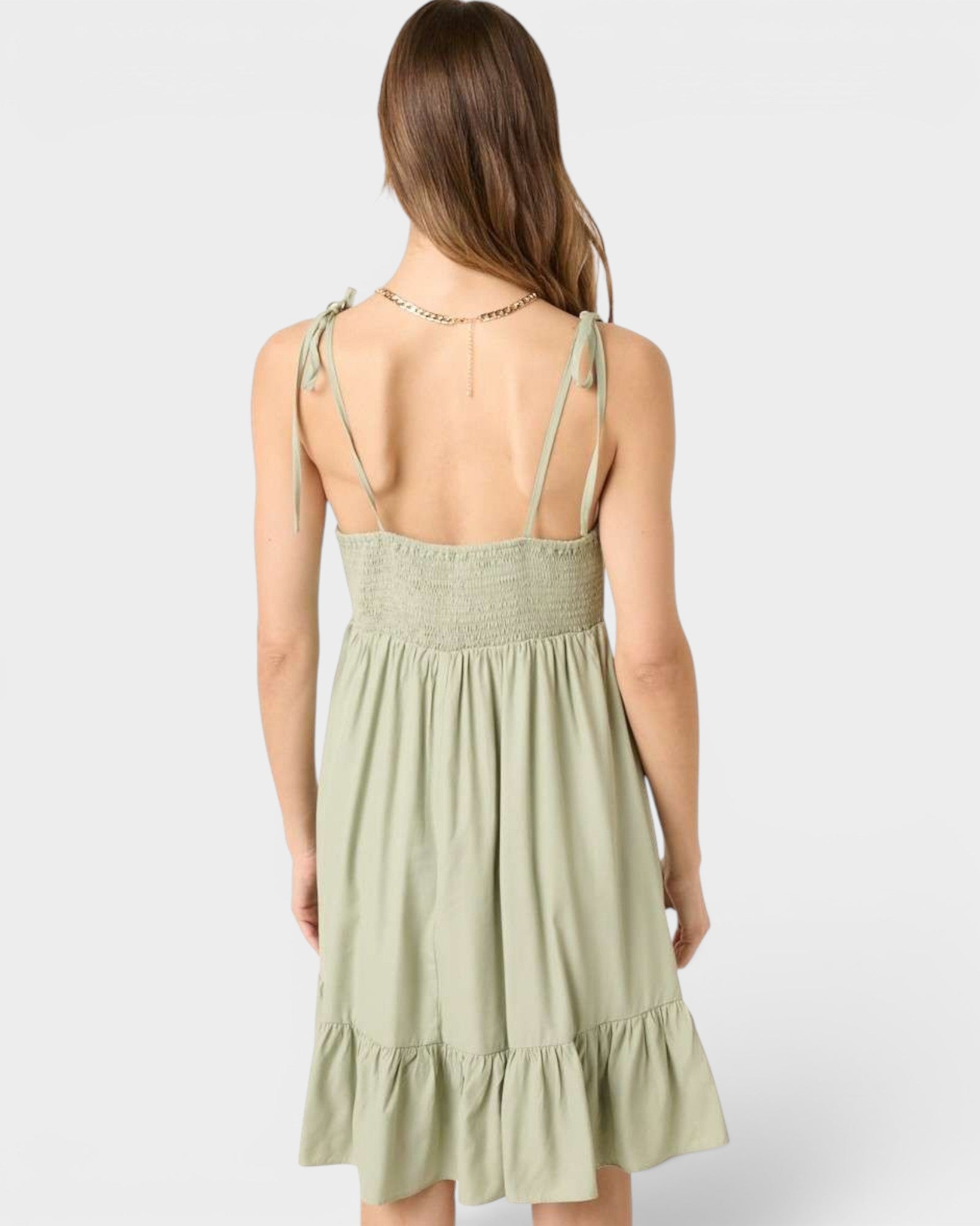 Woman wearing a light green dress with thin straps on a white background